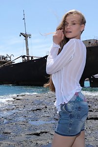 Sexy blonde lifts up her skirt by a shipwreck