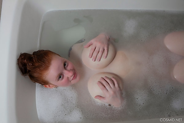 Busty redhead with pale skin bathing