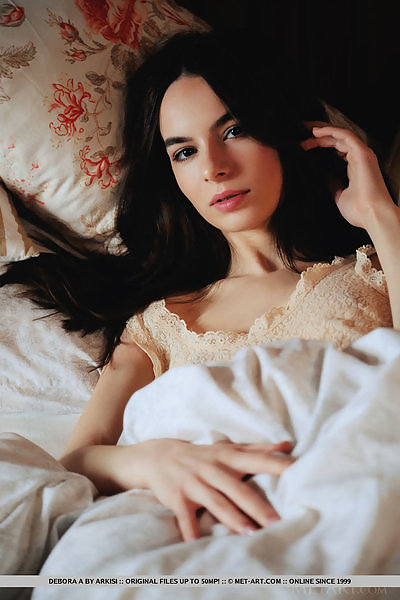Petite black-haired babe Debora Alta spreading in bed