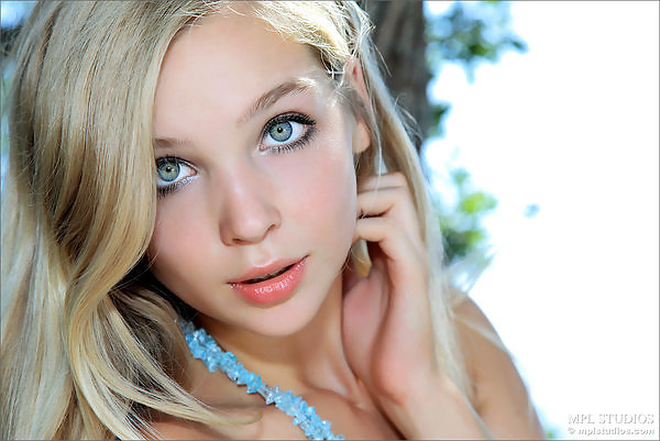 Gorgeous blonde teen with blue eyes nude by a tree