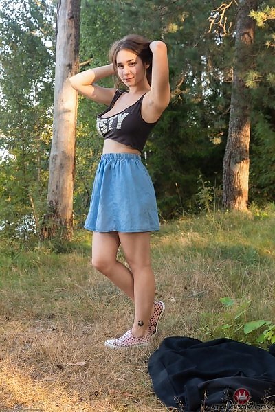 Busty brunette lifts up her dress by a forest
