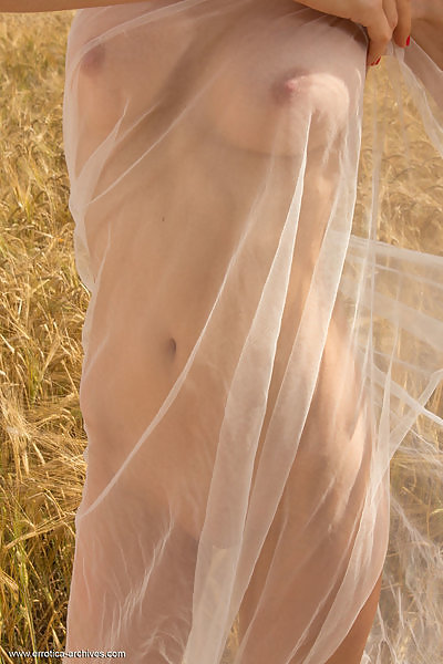 Freckled redhead shows off her bald pussy in a field