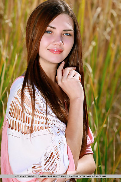 Brunette teen with blue eyes nude in a field