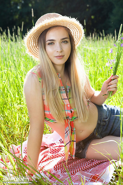 Shaved blonde teen takes off her jean shorts in a field