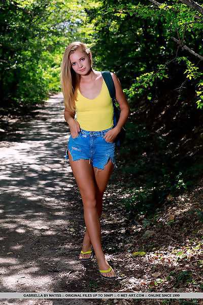 Adorable blonde teen takes off her jean shorts in a forest