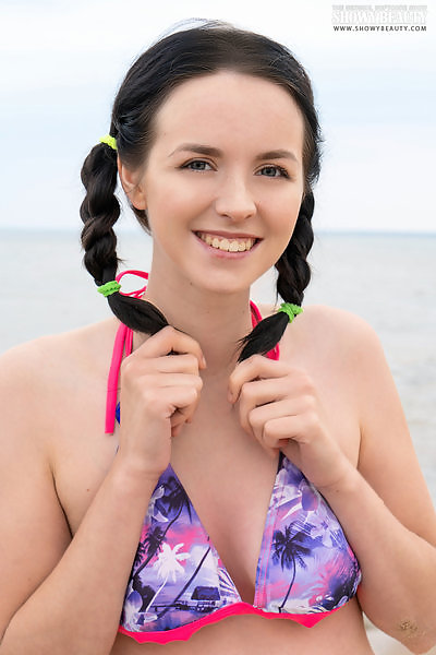 Black-haired teen takes off her bikini at the beach