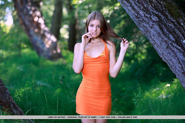 Cute teen with firm tits lifts up her dress in a forest