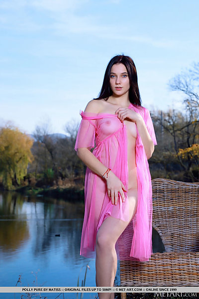Shaved brunette with blue eyes nude by a lake