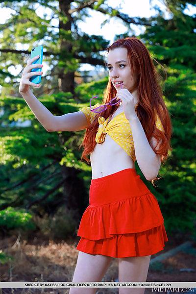 Skinny redhead lifts up her skirt in a forest