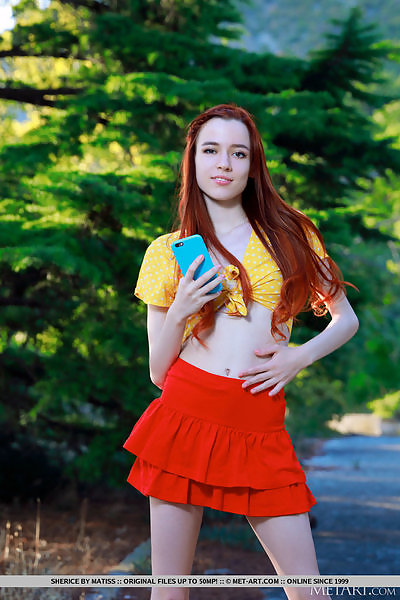 Skinny redhead lifts up her skirt in a forest