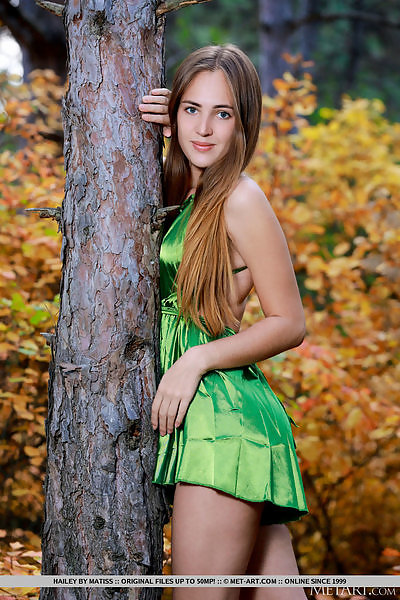 Blue-eyed teen takes off her green dress in a forect