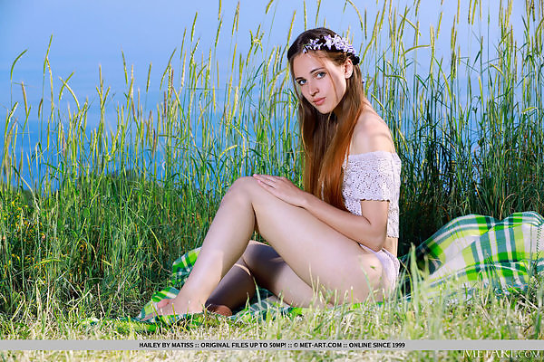 Shaved teen with long hair stripping in a field