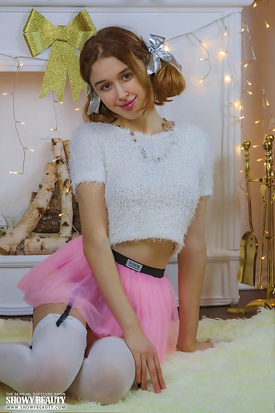 Cute teen with pigtails lifts up her skirt by the Christmas tree