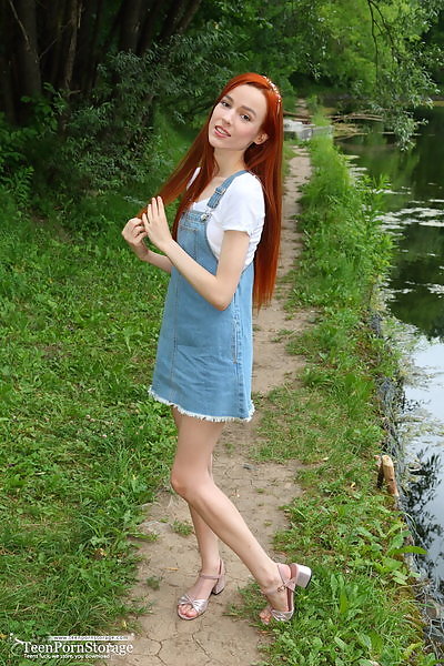 Skinny redhead pulls down her panties by a pond
