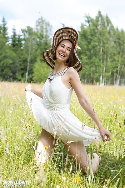 Brunette teen takes off her dress in a field
