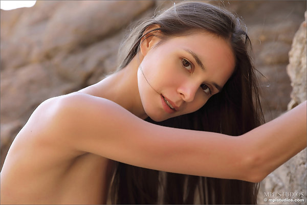 Skinny brunette teen nude by a cliff

