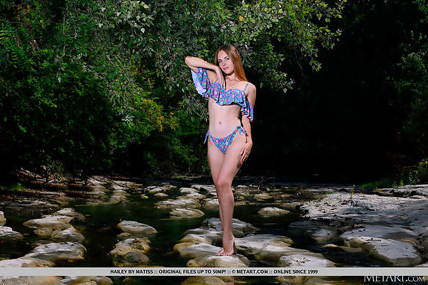 Shaved girl with puffy nipples takes off her bikini by a creek