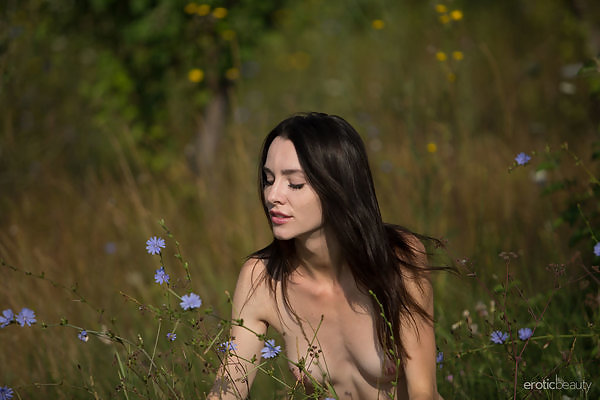 Skinny brunette takes off her dress in a field