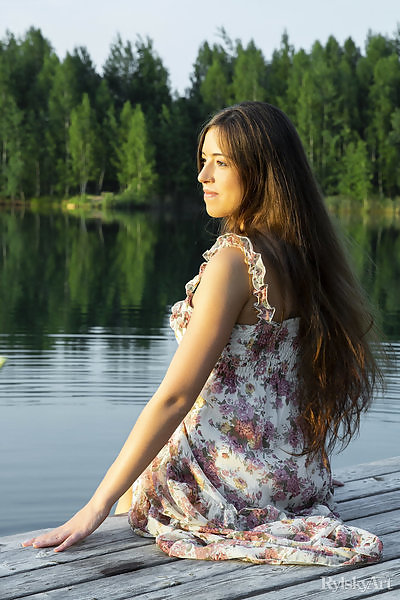 Long-haired brunette lifts up her dress on a dock