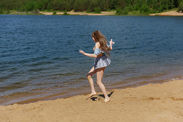 Cute girl lifts up her skirt by a lake
