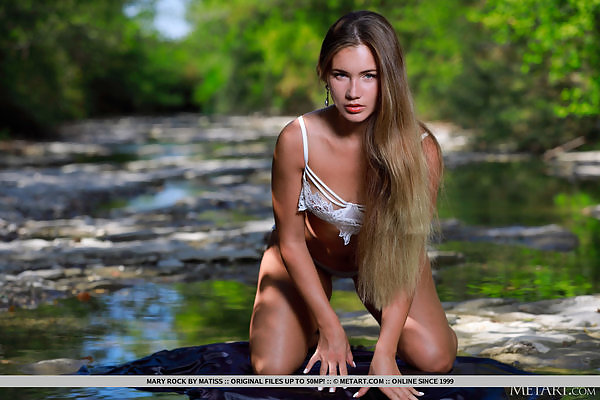 Gorgeous blonde with blue eyes nude in a creek