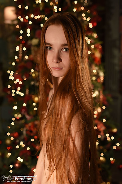 Cute redhead nude by the Christmas tree
