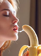 Gorgeous flat-chested redhead sucking a banana and fingering her pussy