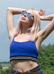 Pale blonde takes off her jean shorts outdoors