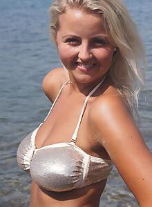 Busty blonde in a see-through top at the beach