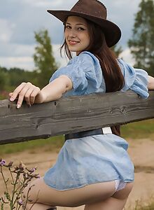 Brunette cowgirl pulls down her panties in a field