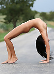 Flexible brunette nude on a street
