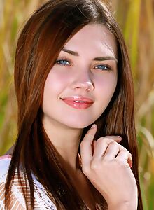 Brunette teen with blue eyes nude in a field