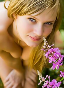 Cute blonde with blue eyes nude in a field