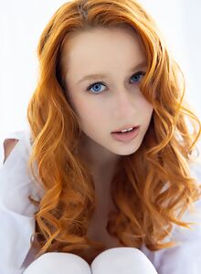 Redhead with blue eyes eyes exposes her bald pussy