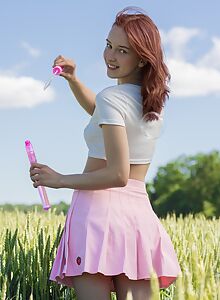 Cute shaved redhead spreading in a field