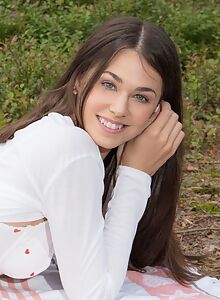 Brunette with blue eyes exposes her shaved pussy in a forest